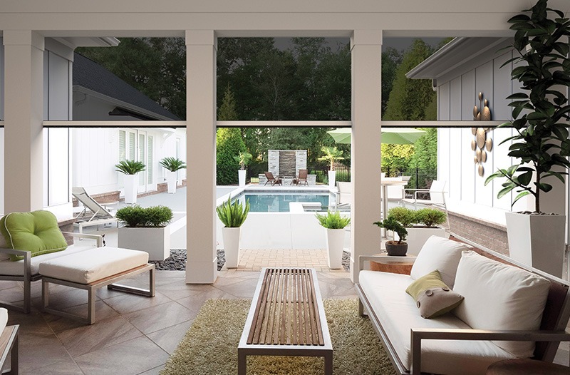 Genius(screens) Modern patio with white furniture and green accents overlooks a swimming pool and landscaped backyard, framed by white columns and potted plants.