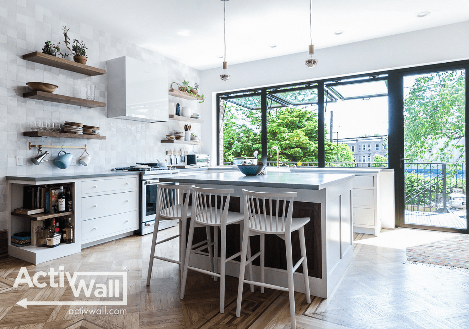 activwallwindow1 Bright and modern kitchen with an island, white cabinets, open shelves, and large windows overlooking greenery outside.